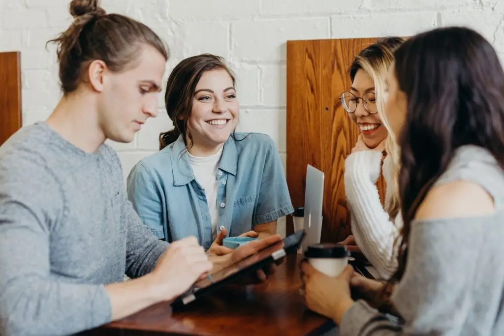 Cuatro jóvenes trabajando con portátil y café